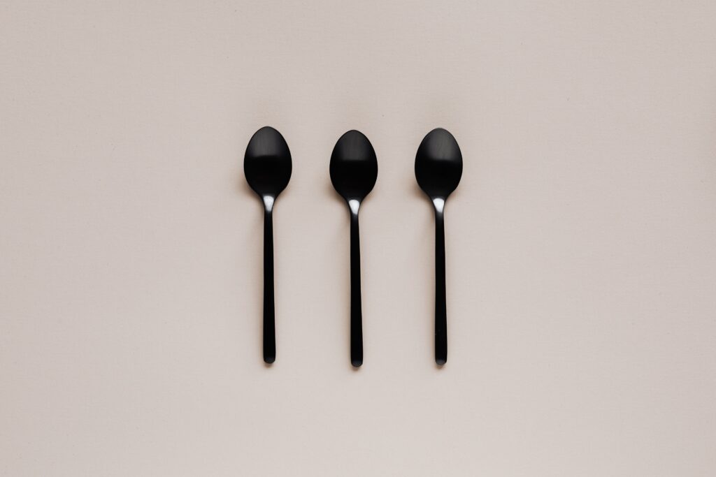 Top view of black teaspoon placed in line on beige background