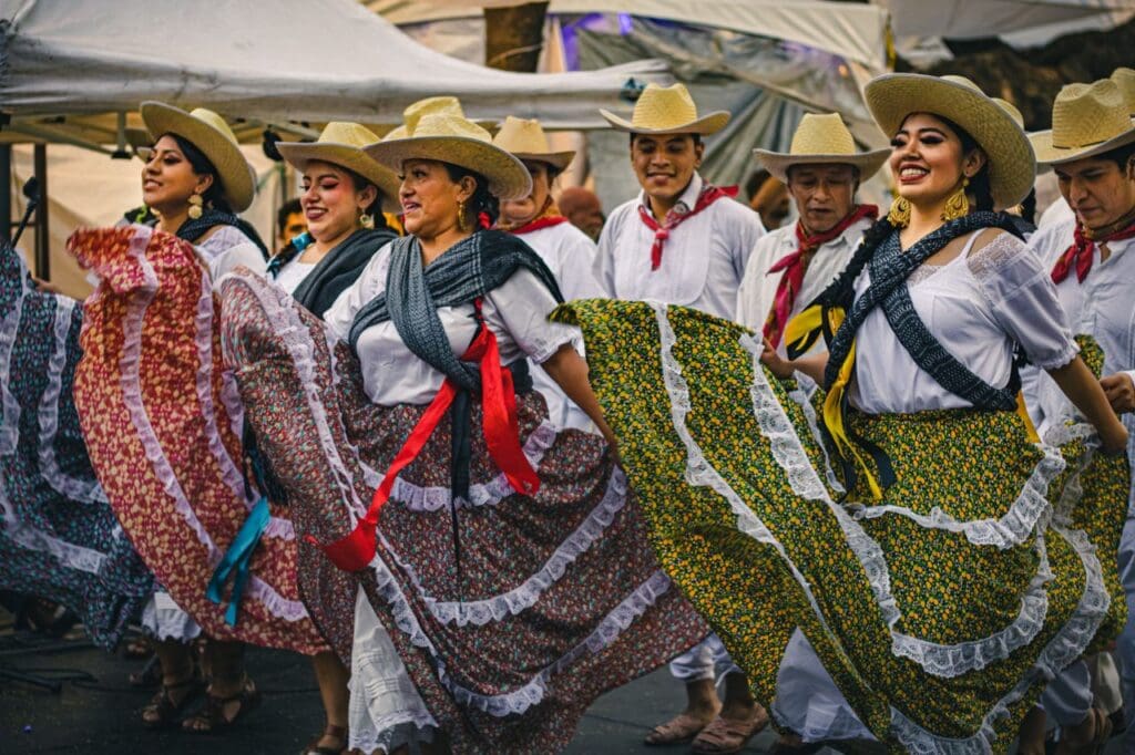 A lively group performing traditional Mexican dance in colorful attire outdoors.
